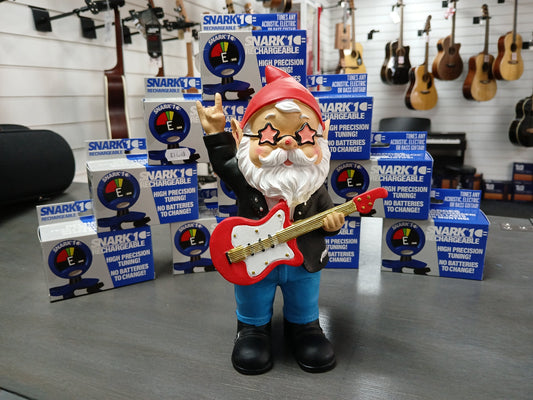 Metro Gnome figurine holding a red guitar surrounded by Snark 1 tuner boxes at Music Bits