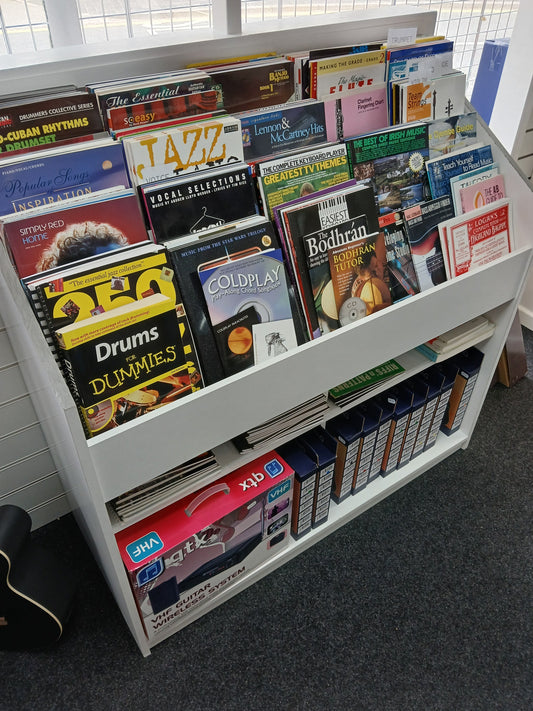 A well-stocked display of sheet music books and music tutors in a music shop, including titles for drums, guitar, jazz, Irish music, and more.