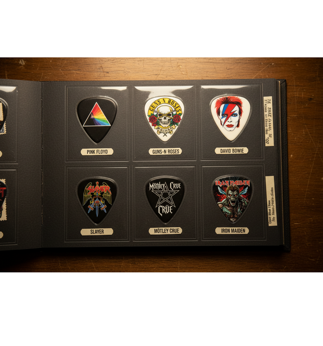 Collection of band artwork guitar picks including Pink Floyd, Guns N Roses, David Bowie, Slayer, Mötley Crüe and Iron Maiden displayed in a collector's album